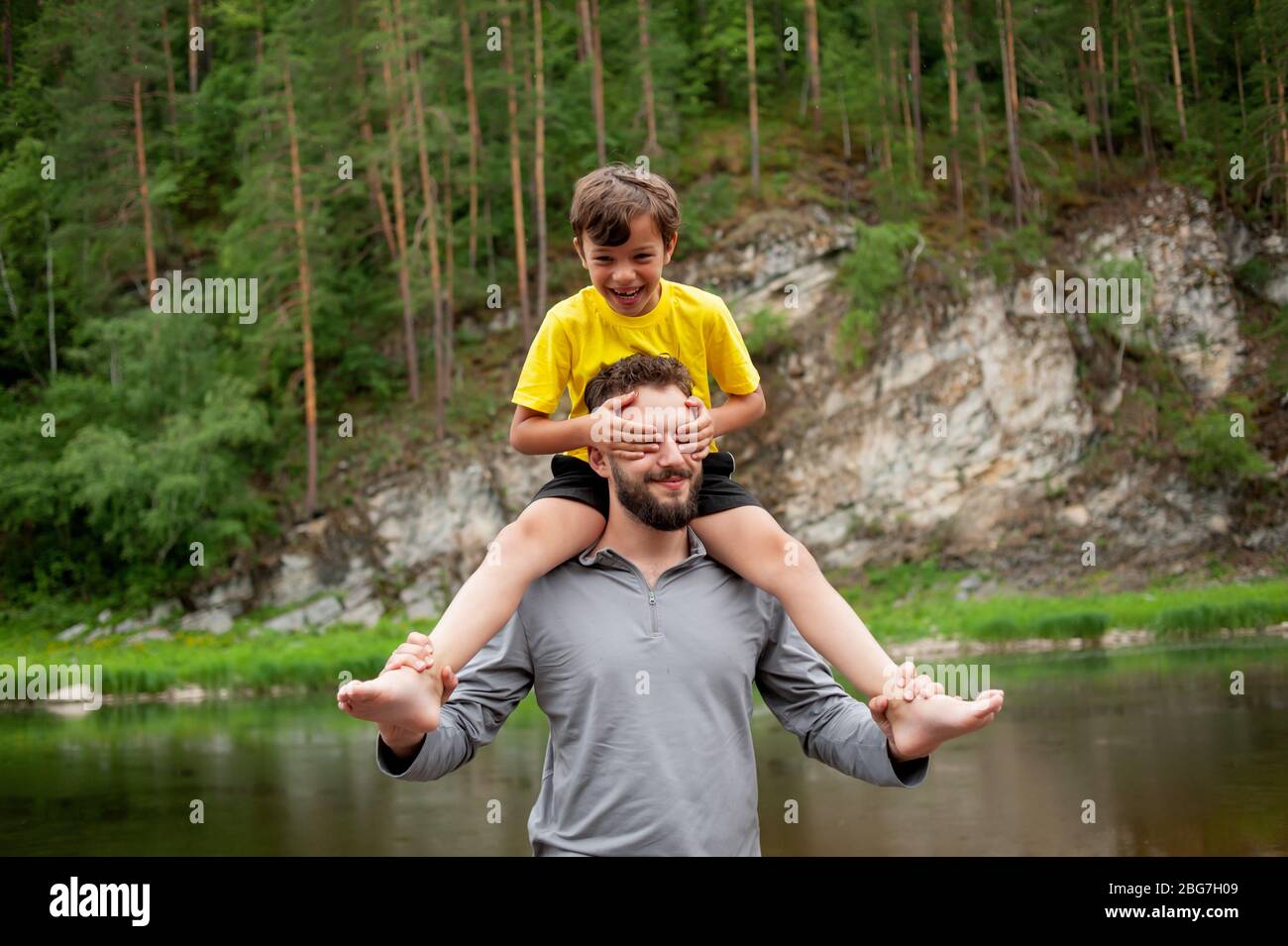 Father and son are smiling while spending time together. Little boy sits on father neck Stock Photo