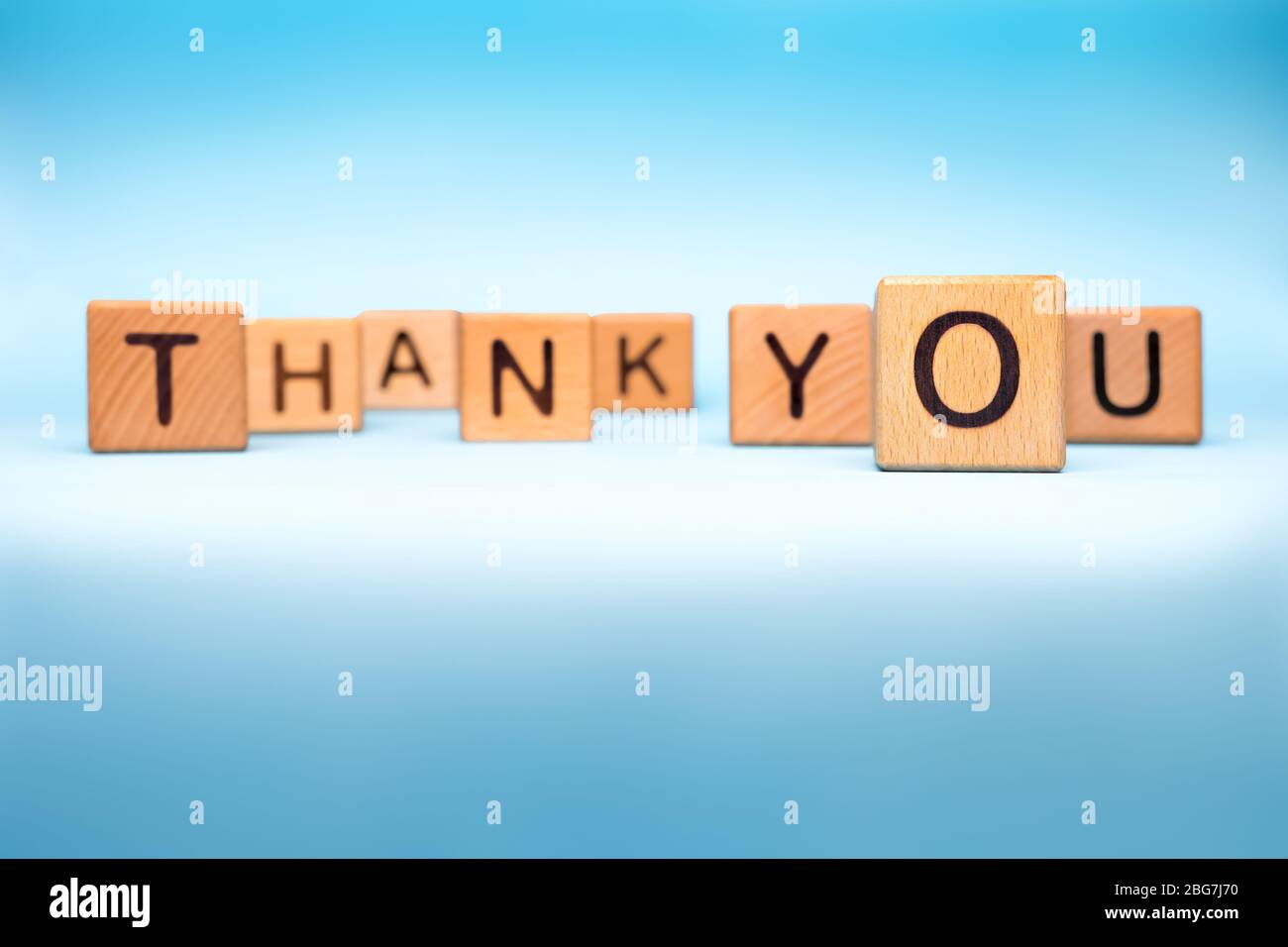 Thank you background. Word thank you made with wooden cubes on blue background. Message of gratitude thanks to helpers. Gratitude concept Stock Photo