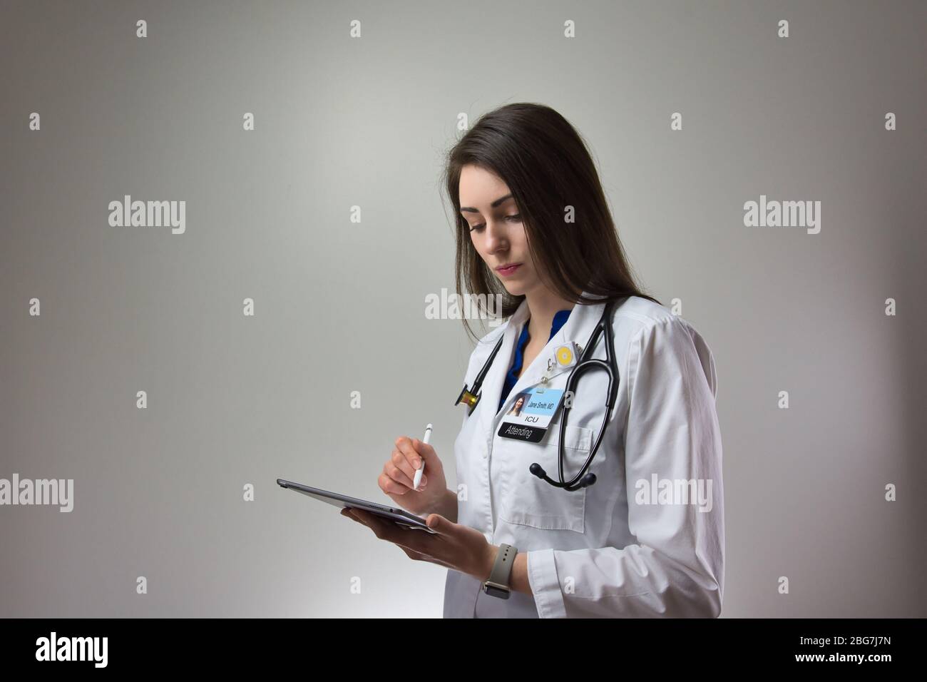ICU Doctor Making Notes In Patient Chart Using Technology Stock Photo