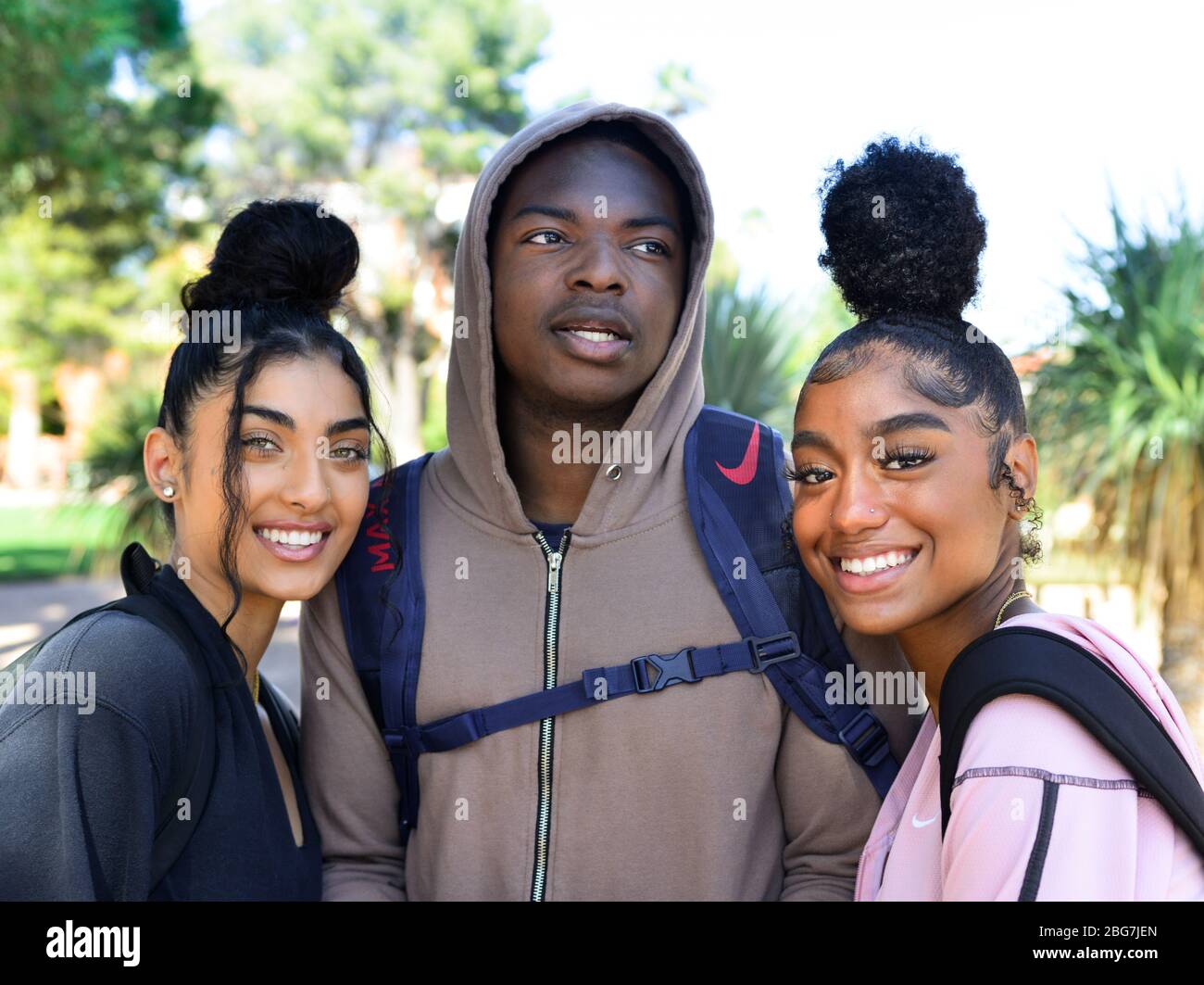 Beautiful young women and man of color, enjoy campus life as students with hoodie and trendy updo hairstyles and smiles in Arizona, USA Stock Photo
