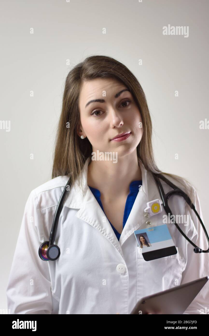 Female physician on grey background. White coat, stethoscope, badge