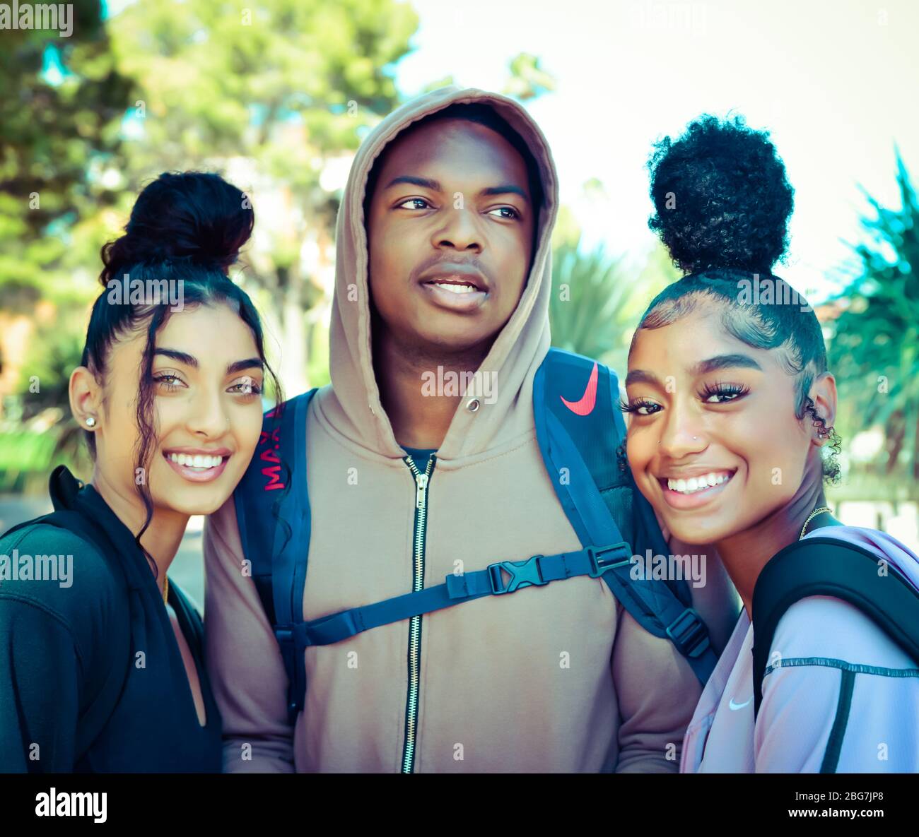 Beautiful young women and man of color, enjoy campus life as students with hoodie and trendy updo hairstyles and smiles in Arizona, USA Stock Photo