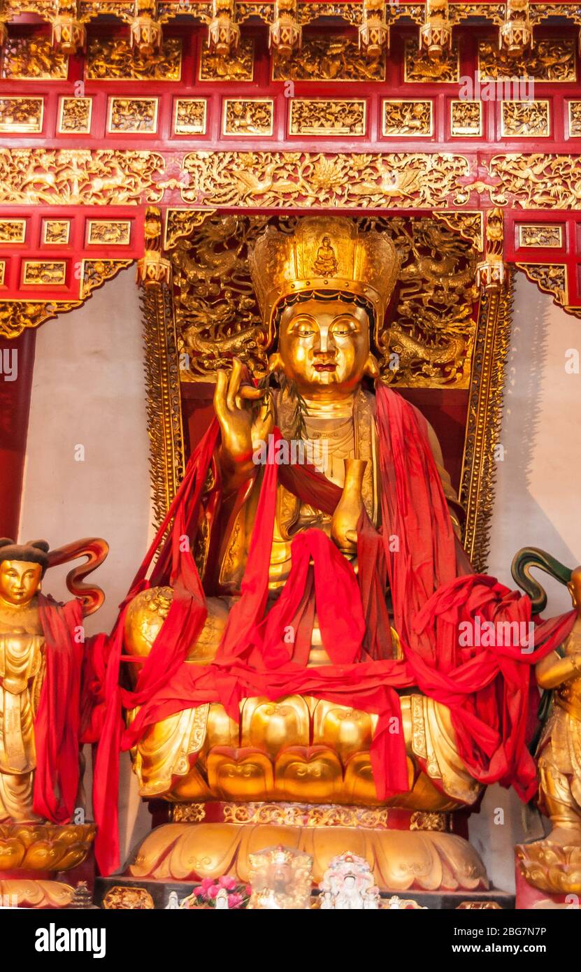 Fengdu, China - May 8, 2010: Ghost City, historic sanctuary. Gold and red and nothing else colors on lotus sitting Buddha statue in niche under baldac Stock Photo