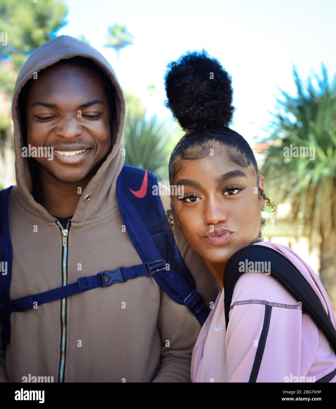 A smiling man and beautiful young woman of color, enjoy campus life with  her sassy attitude and puckered lips with trendy up-do hairstyle, Tucson, AZ Stock Photo