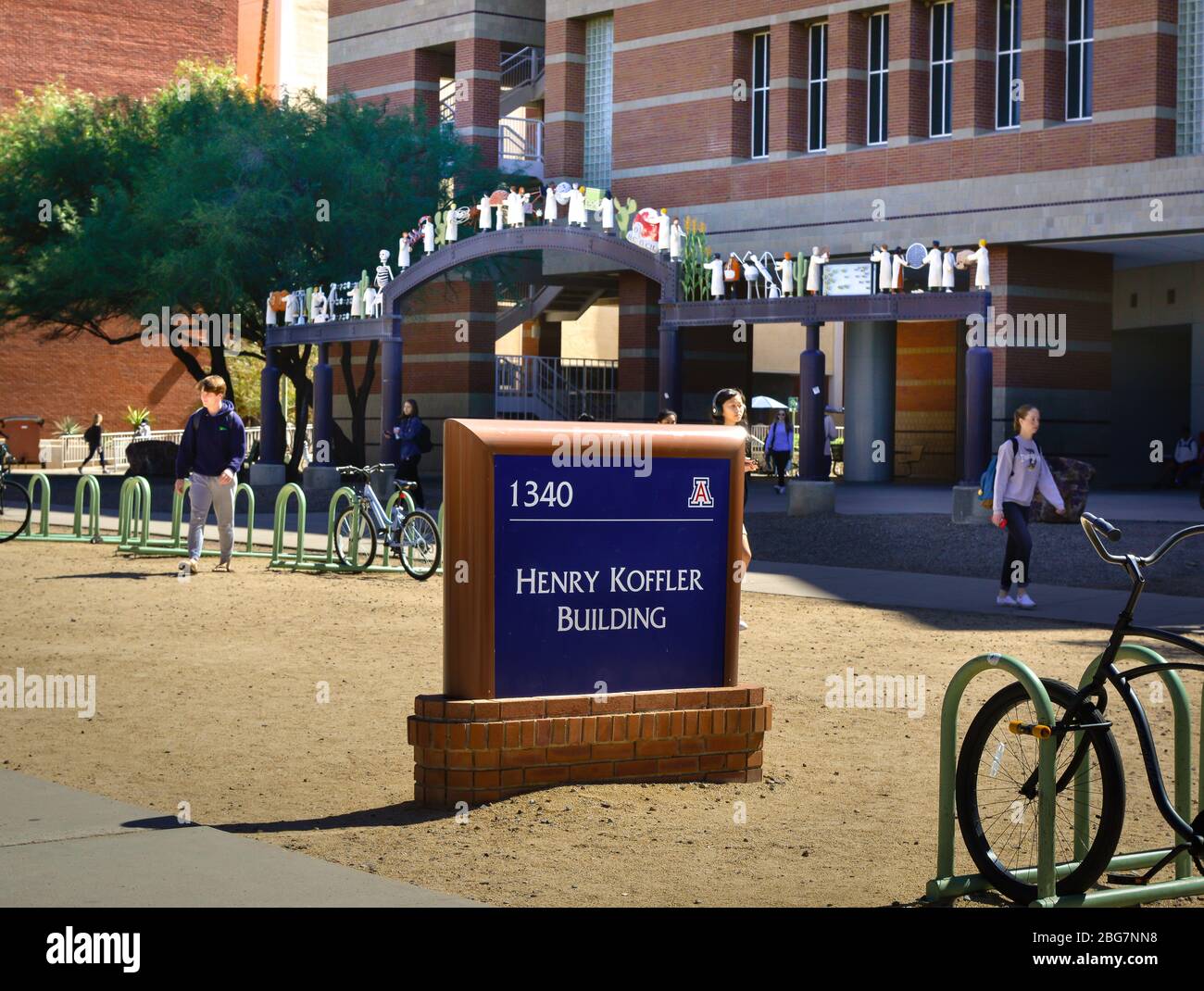 Bikes and students with sign for the Henry Koffler Building's archway