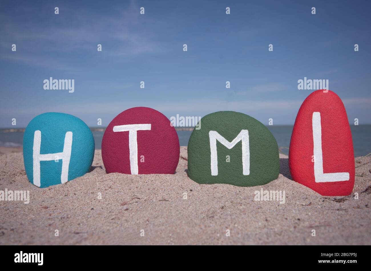 HTML, HyperText Markup Language composed with multi colored stone letters on the beach Stock Photo