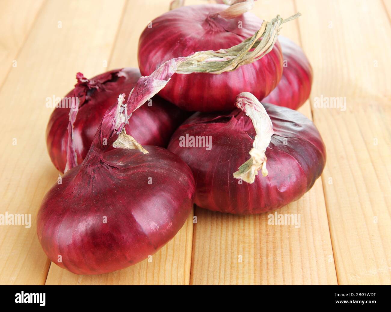 Fresh red onions on wooden table Stock Photo - Alamy