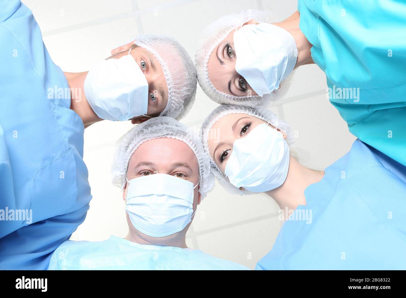 View from below of surgeons in protective work wear during operation Stock Photo