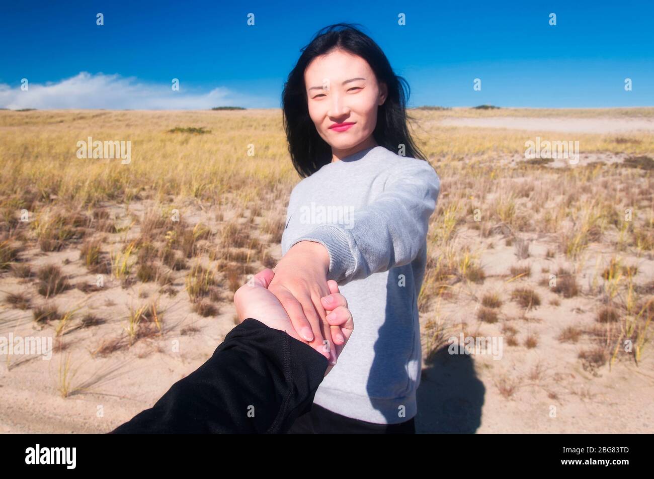 A chinese woman holding hands with a man focus point on the hands with blurred face on within the national seashore scenic area in Cape Cod, Massachus Stock Photo