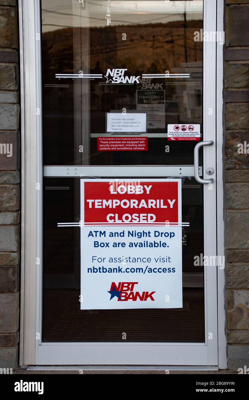 A sign in the door of a NBT Bank branch in Speculator, NY indicating the bank lobby is temporarily closed due to the coronavirus. Stock Photo