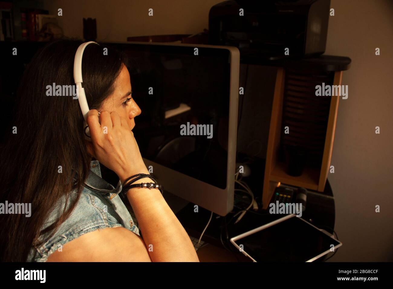 Caucasian woman between 40 and 45 years adjusting the headband on her head to listen to a conference in her home office work Stock Photo