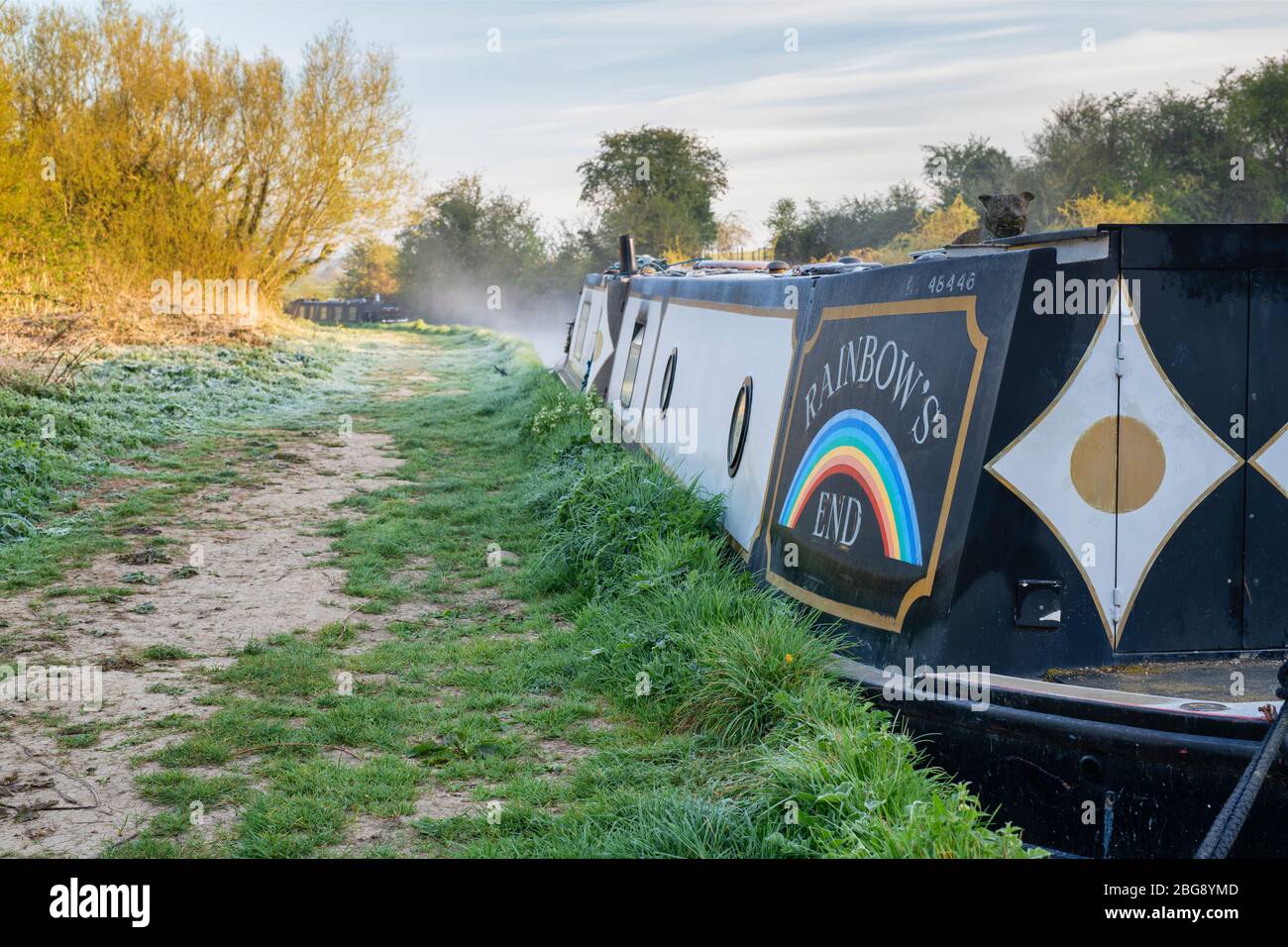 Canal boat called Rainbows End in the mist on the oxford canal on a spring morning at sunrise. Lower Heyford, Oxfordshire, England Stock Photo