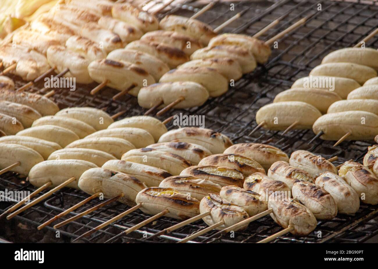 banana grill with hot coal to making snack of Thai dessert with wood stick Stock Photo