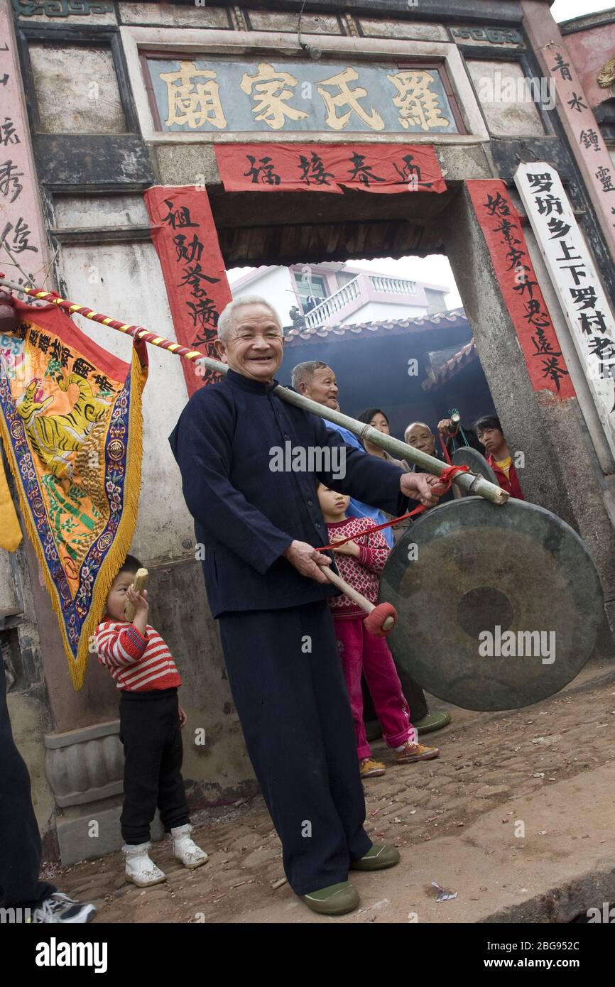 In theLet's Go Ancient activity of the Lantern Festival in 2007 the old man knocking on the gong in front of the Luo Clan Temple Luofang Township Lian Stock Photo