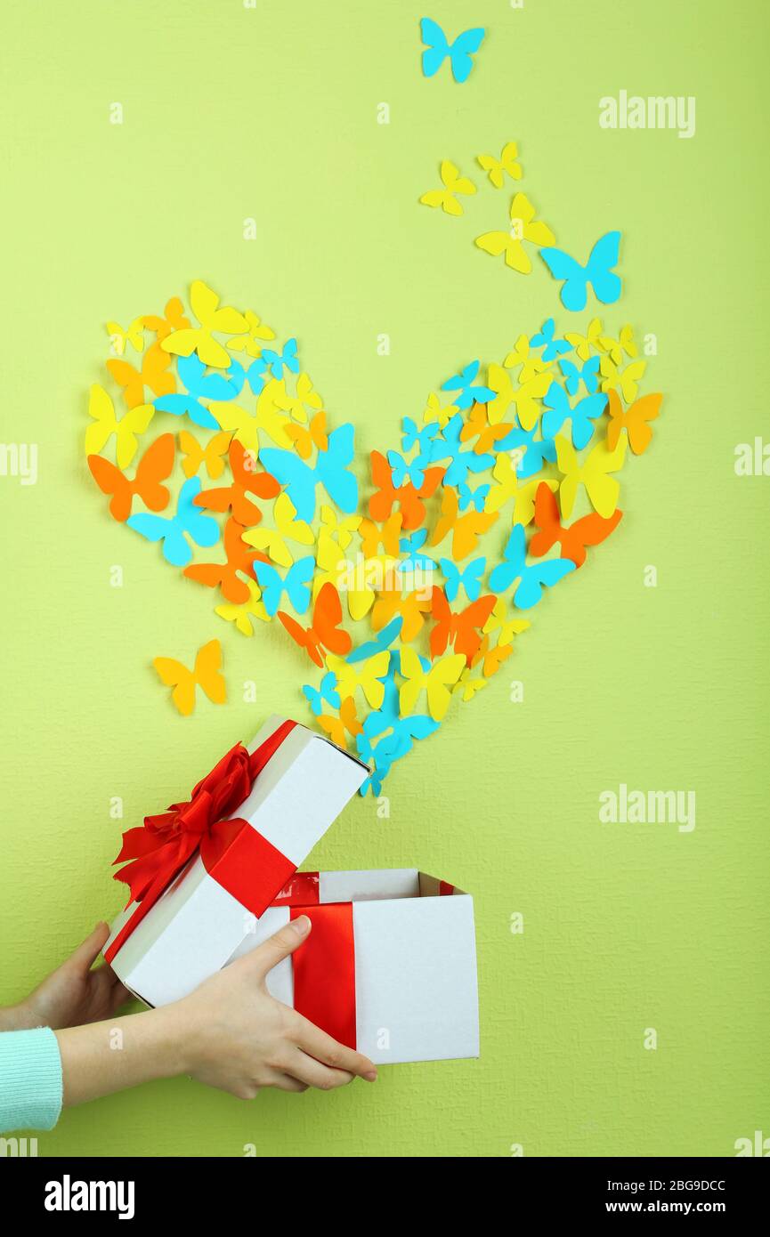 Paper butterflies fly out of box on green wall background Stock Photo