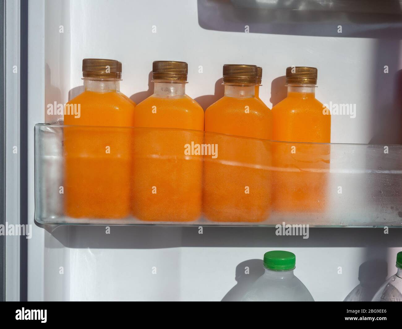 Orange juice iced cold in the bottles on shelf in refrigerator. Square
