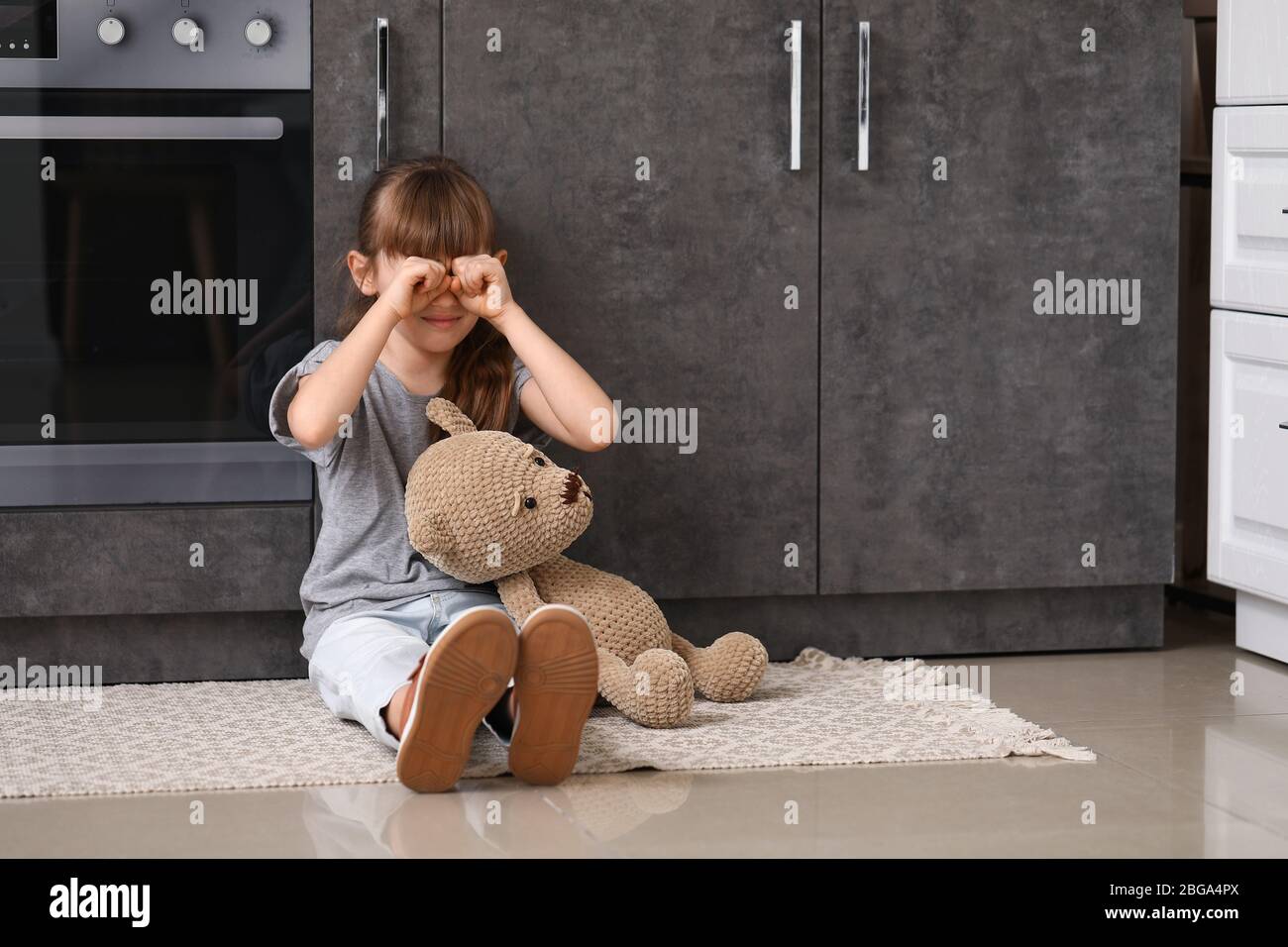 Afraid little girl with teddy bear at home. Concept of domestic violence Stock Photo