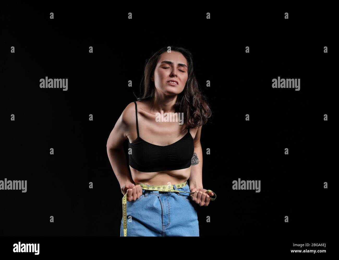 Sick woman measuring her waist on dark background. Concept of