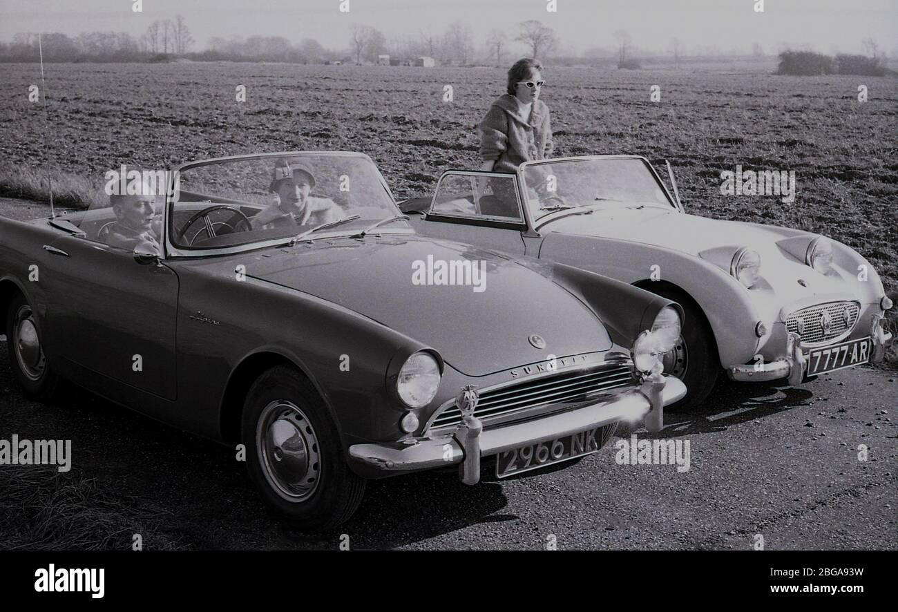 1960s, historical, two couples parked beside a field near Letchworth Garden city sitting in their British made open top sports cars, a Sunbeam Alpine made by the Rootes company and an Austin-Healey Sprite., a smaller roadster. The Sprite, a joint venture between the Austin Co and Donald Healey, was affectionately known as the 'Frogeye' on account of the headlights being positioned unusually on the bonnet of the car. Stock Photo
