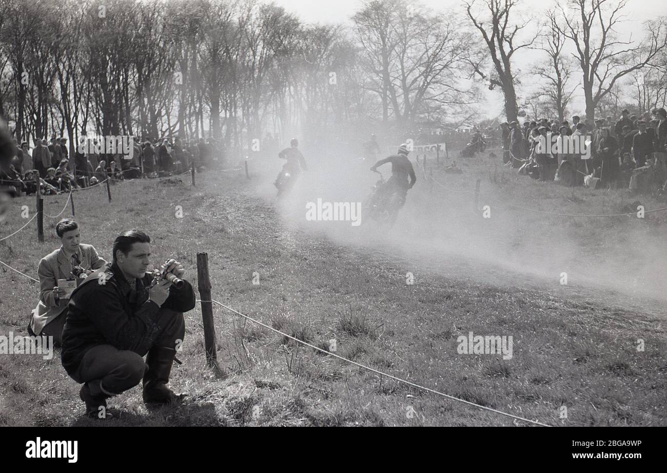 1960s, historical, spectators standing on a hilly ridge, watching an off-road motorcycle scramble race, a sport which later became commonly known as motorcross racing. The first ever official scramble was held in Camberley, Surrey, in 1924. Post-WW2 the sport expanded as motorbikes became lighter and faster. Stock Photo