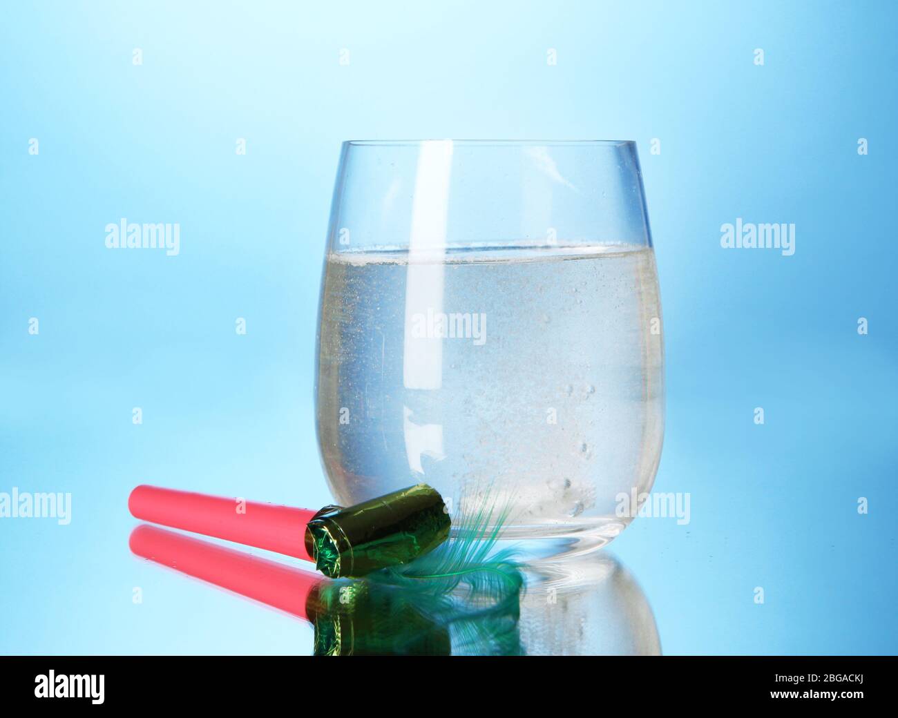 Glass with efervescent tablet in water with bubbles on blue background Stock Photo