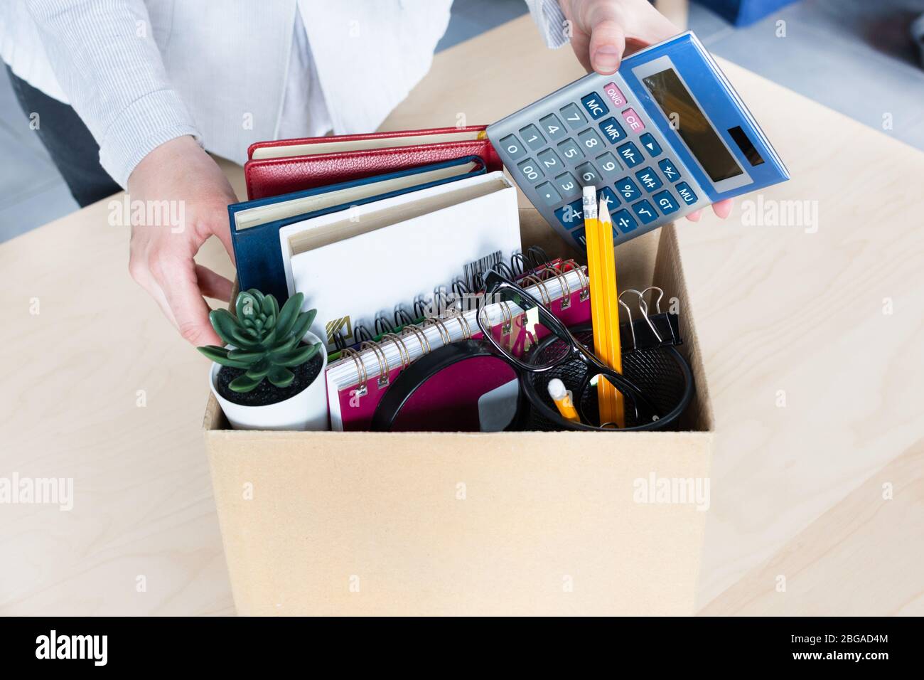 Business woman packing personal company belongings into cardboard box. Dismissal or resignation concept. Company bankruptcy and economy crisis. Stock Photo