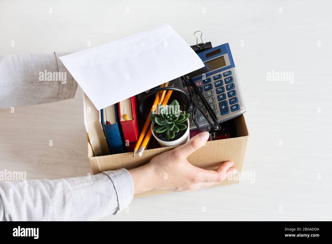 Business woman holding cardboard box with personal company belongings. Dismissal or resignation concept. Company bankruptcy and economy crisis. Stock Photo