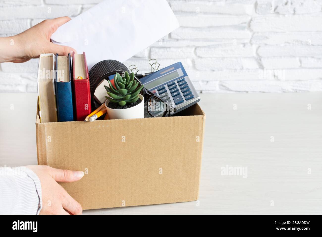 Business woman packing personal company belongings into cardboard box. Dismissal or resignation concept. Company bankruptcy and economy crisis. Stock Photo