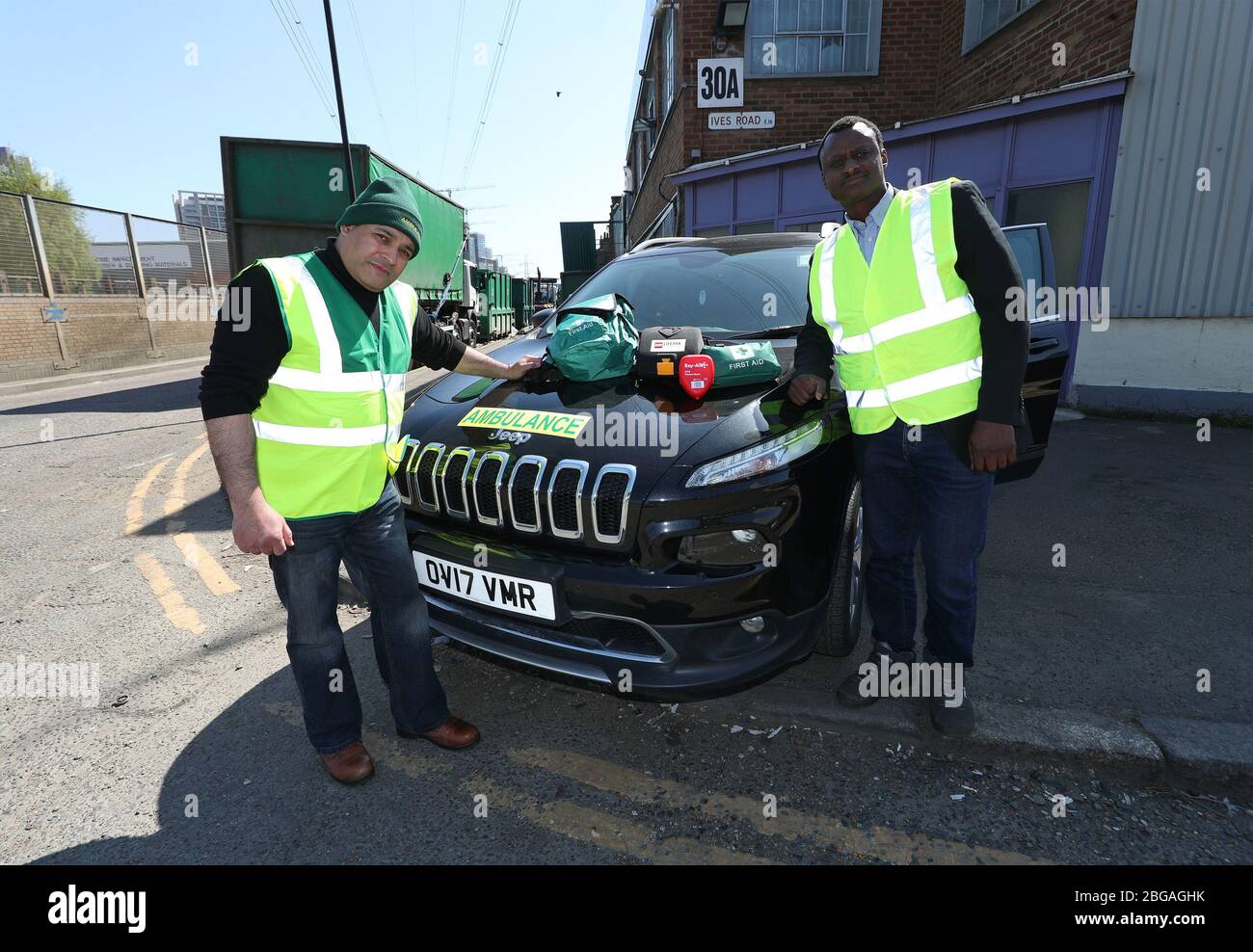 Jonathan Ganesh, president of the Docklands Victims' Association (DVA) and an NHS Volunteer Responder (left) and Ousman Marong, with an ambulance donated by Elite Support Services to support the efforts against the Covid-19 outbreak, in London. Mr Ganesh, a victim of the 1996 IRA bombing which devastated London's docklands, and members of the DVA have registered with the Your NHS Needs You volunteering programme to relieve pressure on the health service providing essential supplies to those who are self-isolating. Stock Photo