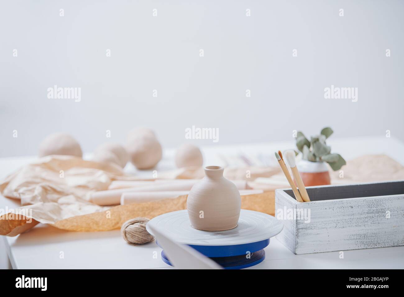 All things pottery. Clay balls, vase on wheel and brushes Stock Photo