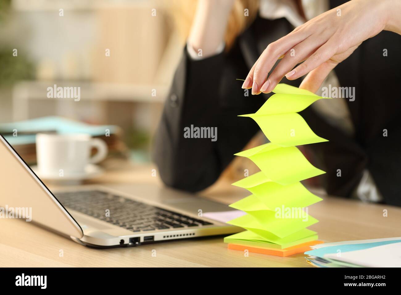 Bored lazy entrepreneur woman hands wasting time with post notes sitting on a desk Stock Photo