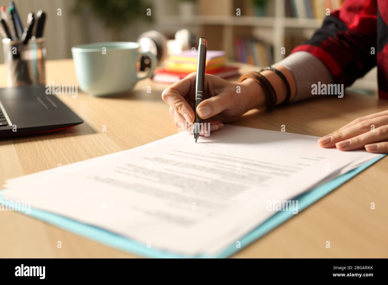 Close up of student girl hand signing contract on a desk at home at ...