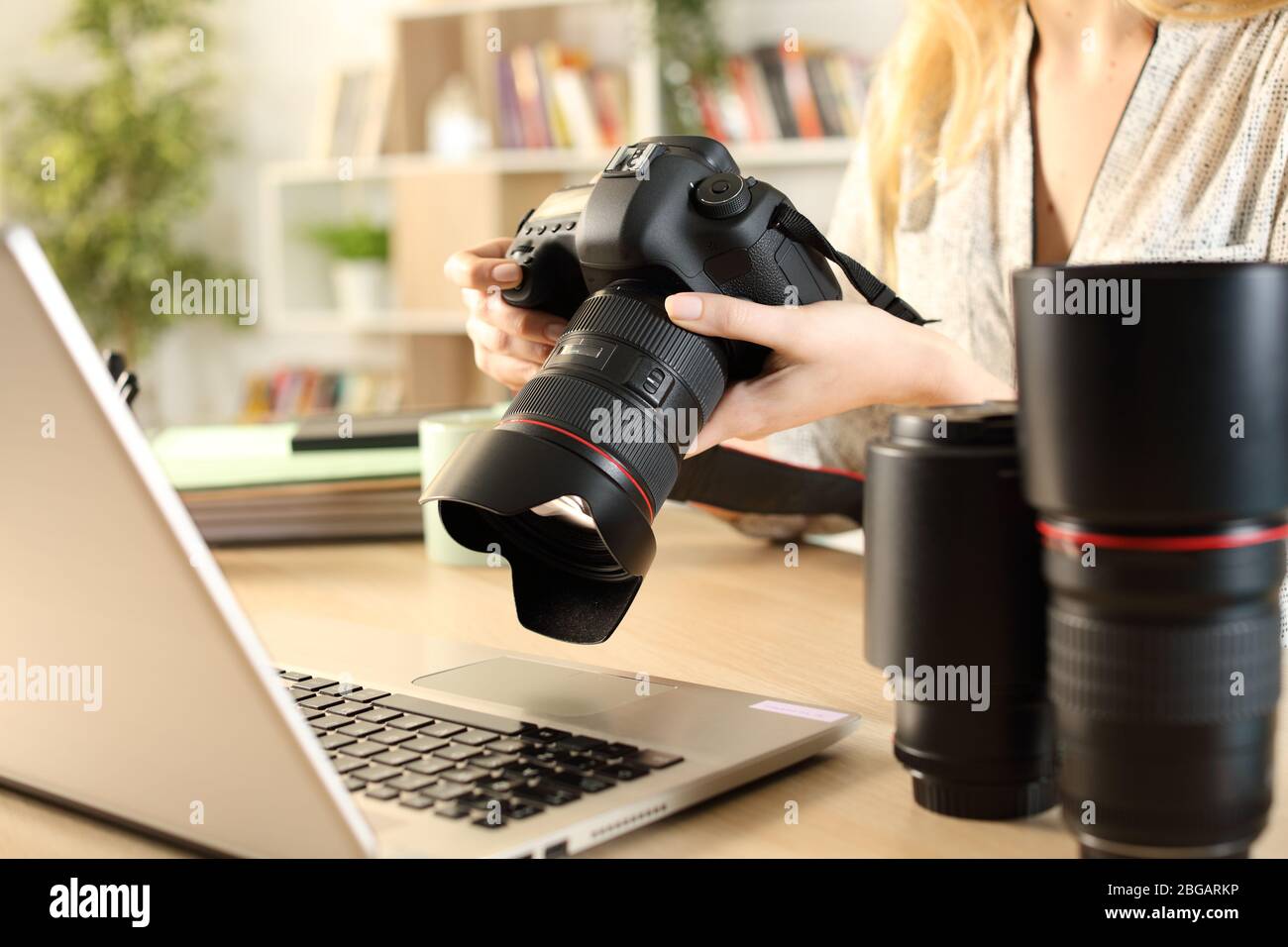 Close up of photographer woman hands with laptop checking dslr camera on a desk at home Stock Photo
