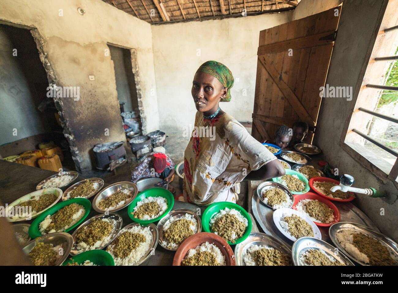 Lamu, Kenya - December 15, 2016: Ultra wide portrait of Black women with many dishes full of food in a basic kitchen Stock Photo