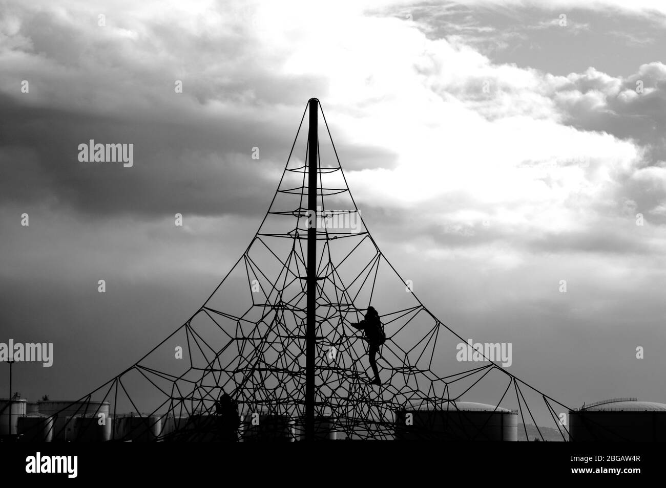 A crocheted web of ropes against the sky. Rope climbing toys for kids in outdoor playground. Complicated connections or network concept. Stock Photo