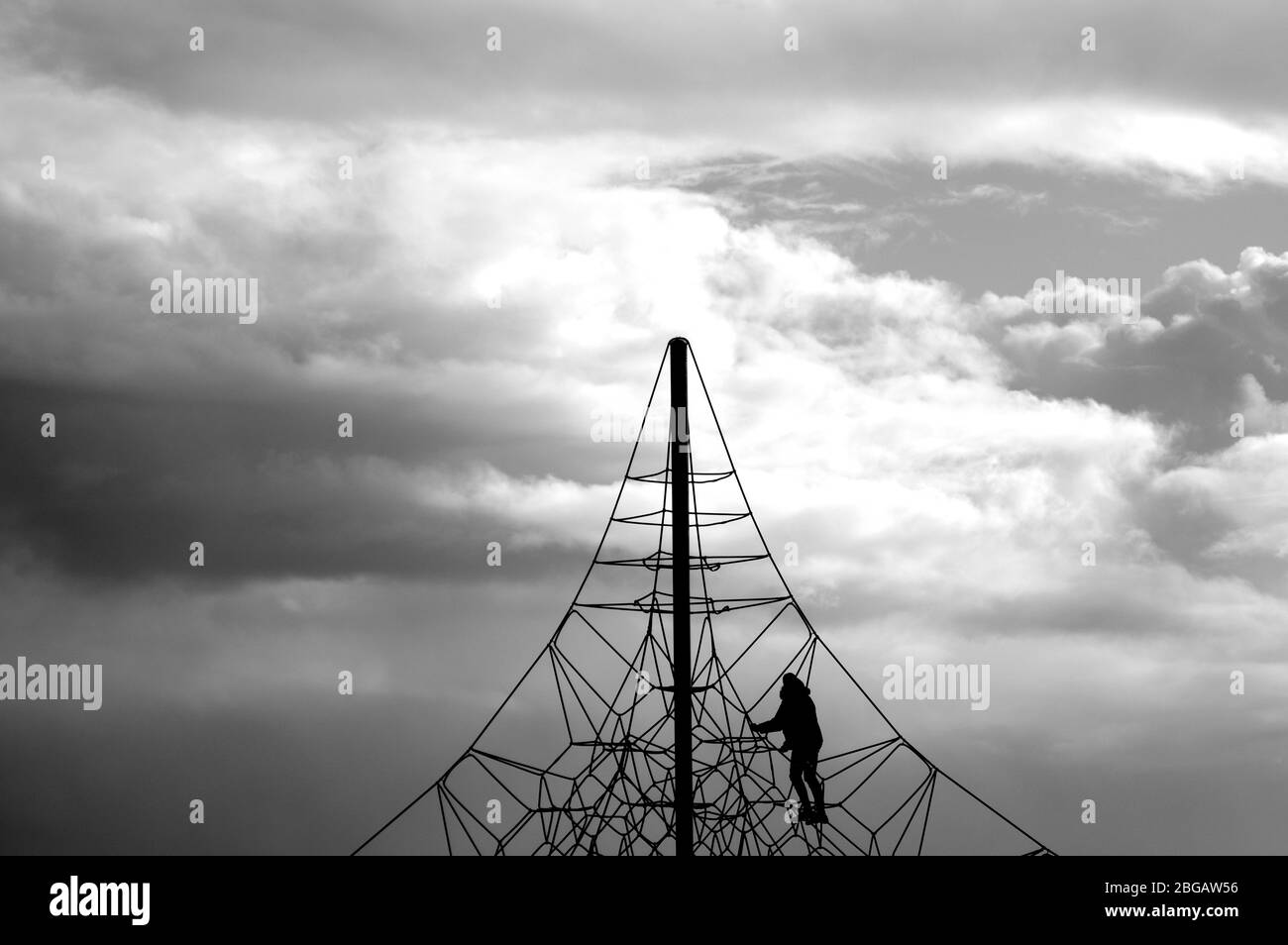 A crocheted web of ropes against the sky. Rope climbing toys for kids in outdoor playground. Complicated connections or network concept. Stock Photo