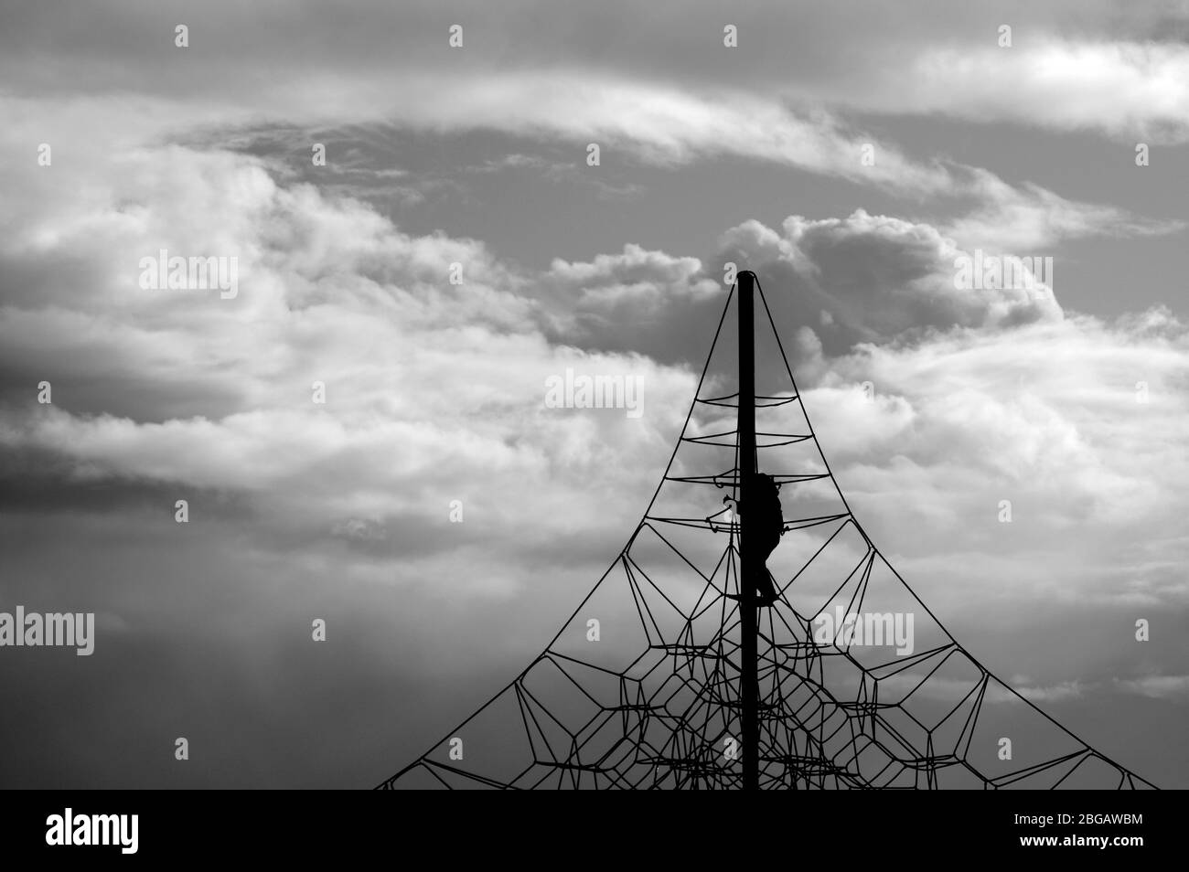 A crocheted web of ropes against the sky. Rope climbing toys for kids in outdoor playground. Complicated connections or network concept. Stock Photo