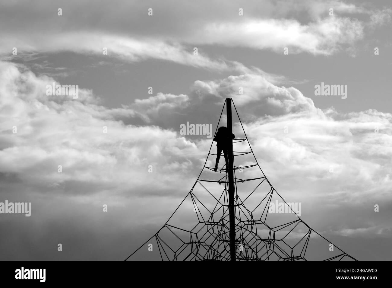 A crocheted web of ropes against the sky. Rope climbing toys for kids in outdoor playground. Complicated connections or network concept. Stock Photo