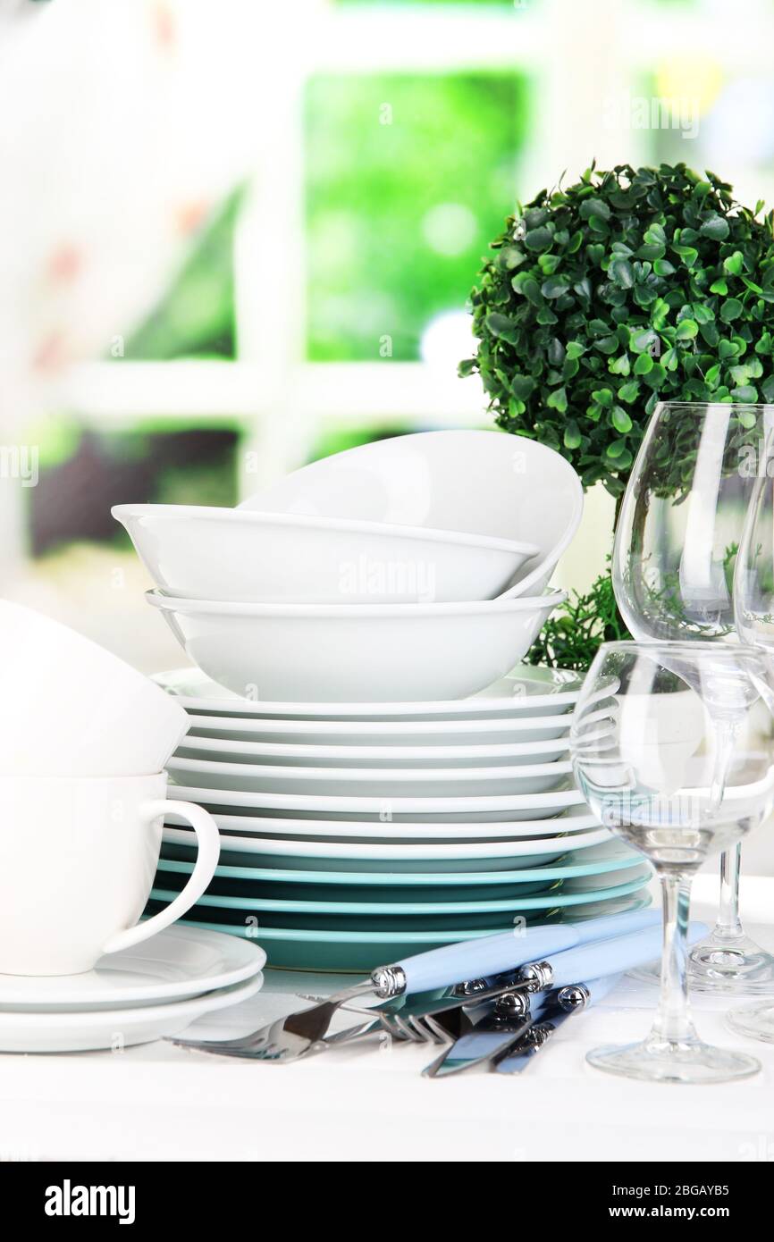 Clean dishes on table on window background Stock Photo - Alamy