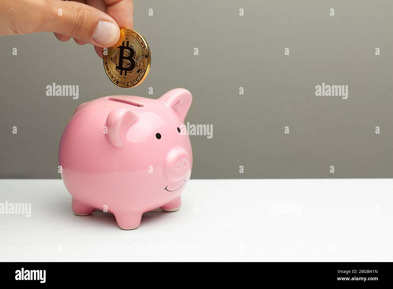 Pink piggy bank and golden bitcoin on a gray background. Cryptocurrency  Savings. Copy space for text Stock Photo - Alamy