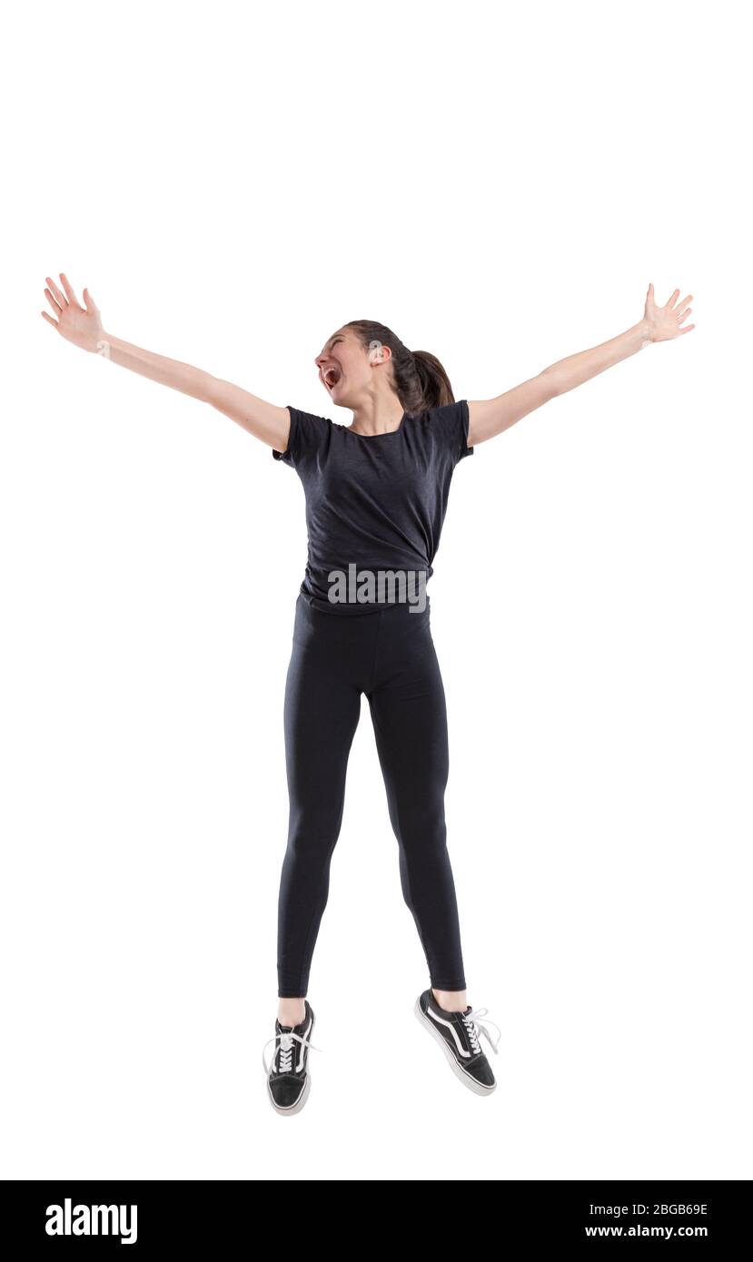 Exuberant laughing vivacious young woman jumping for joy with outstretched arms isolated full length on white Stock Photo