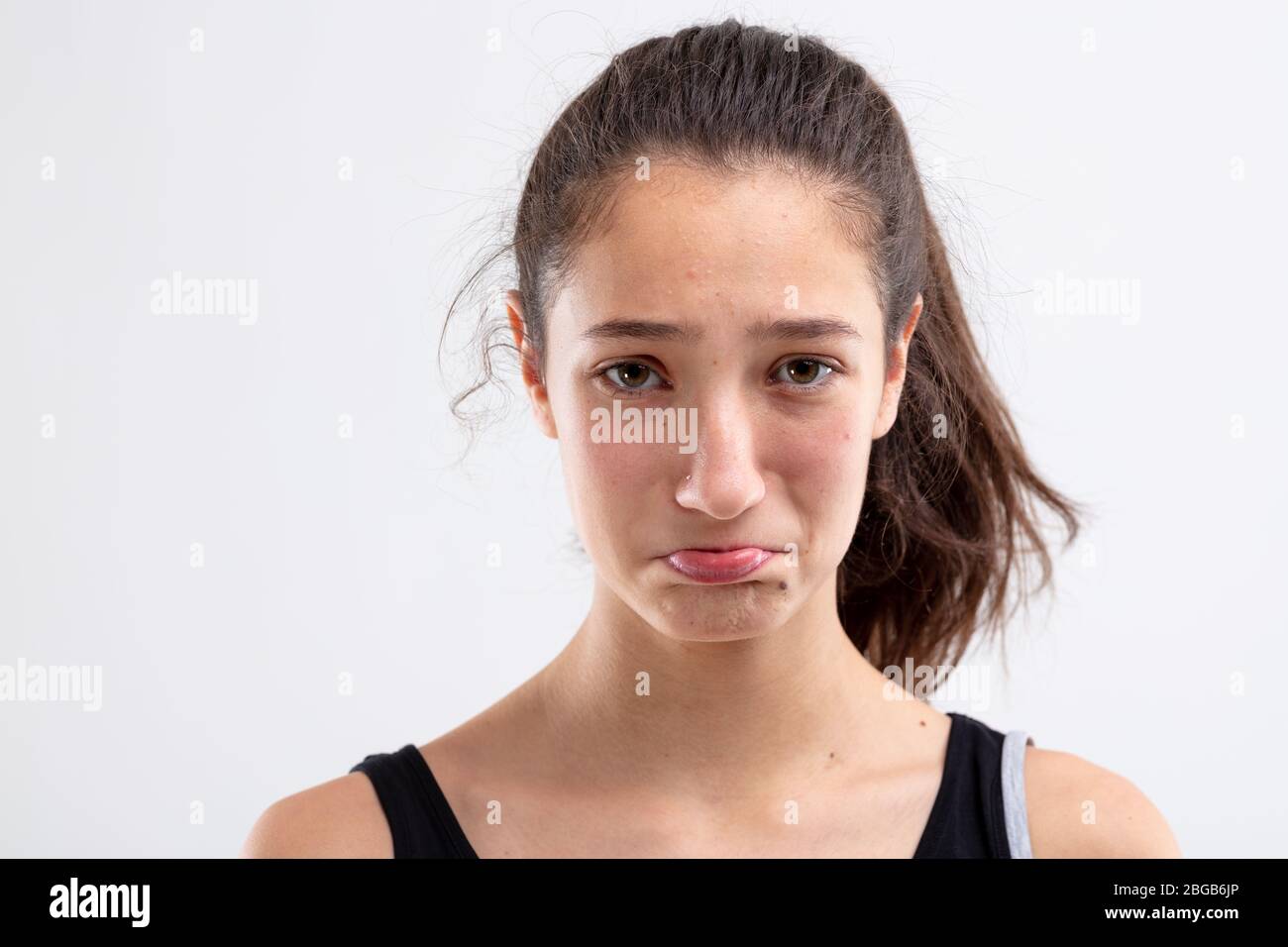 Sulky miserable young woman pouting her lips and looking at the camera with sorrowful eyes in a close up head shot on white Stock Photo