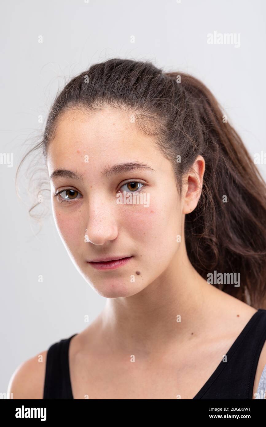 Thoughtful earnest young woman staring at the camera with a serious calm expression in a close up head shot on white Stock Photo