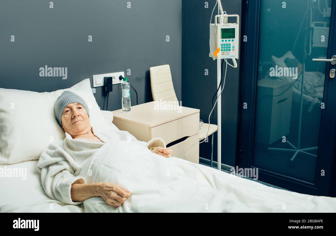 Elderly woman in a oncology clinic ward receiving chemotherapy treatment. IV drip for chemotherapy Stock Photo