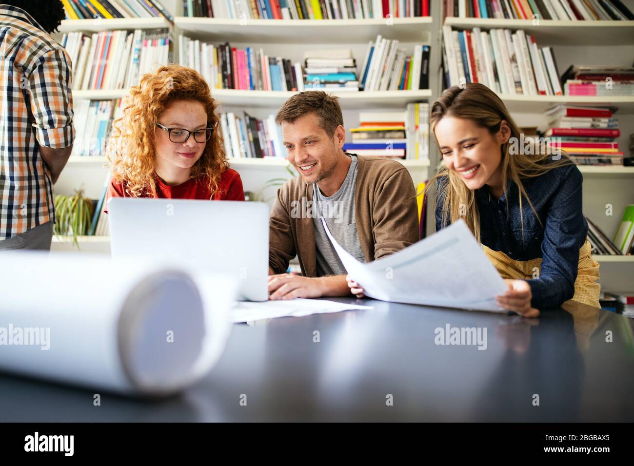 Young architect colleagues are analyzing blueprints while working on a new project Stock Photo