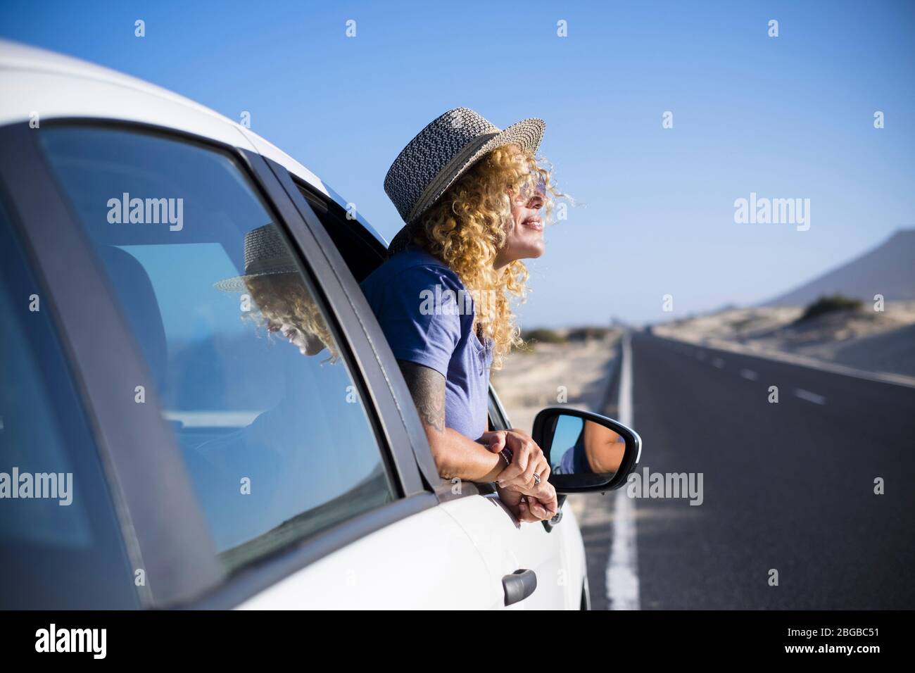 Happy freedom concept with beautiful lonely traveler adult caucasian woman enjoy the trip lifestyle outside the window of her white car - transport an Stock Photo