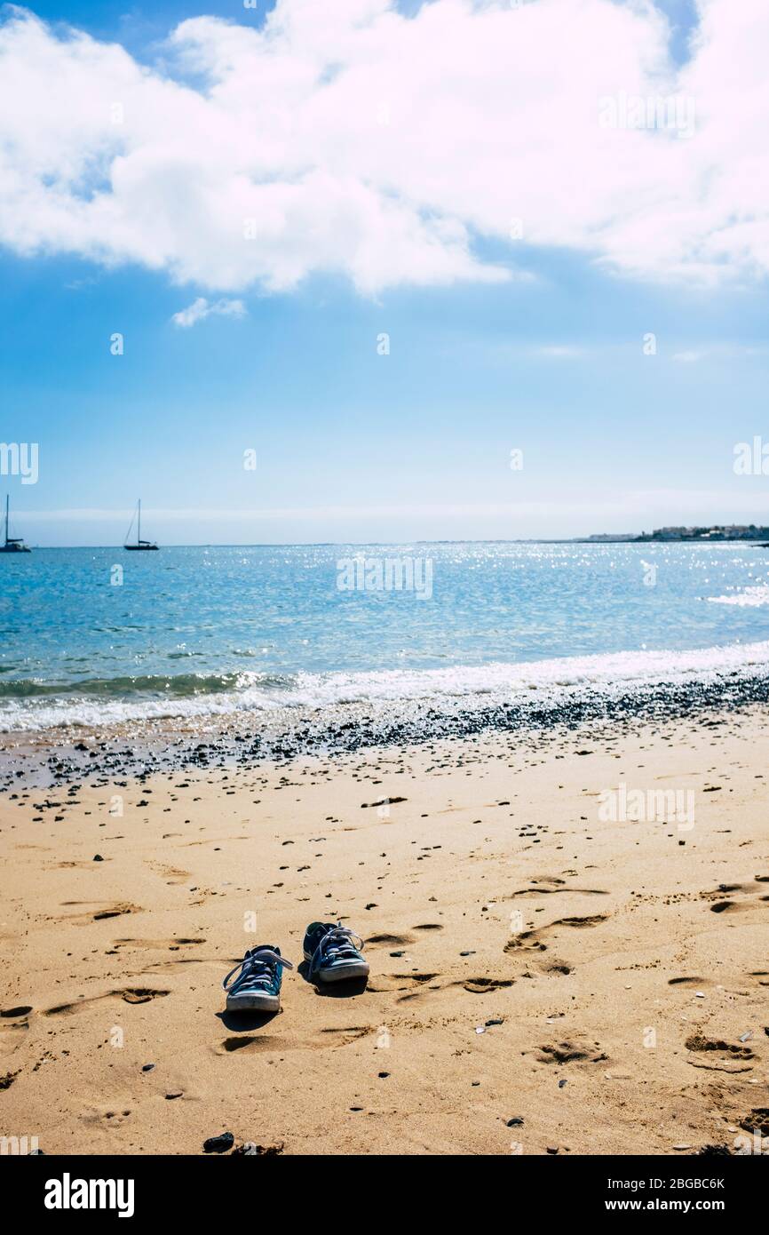 Tourism and summer holiday vacation concept with pair of shoes on the sand at the beach near blue sea water and under a beautifulsky - travel and peop Stock Photo