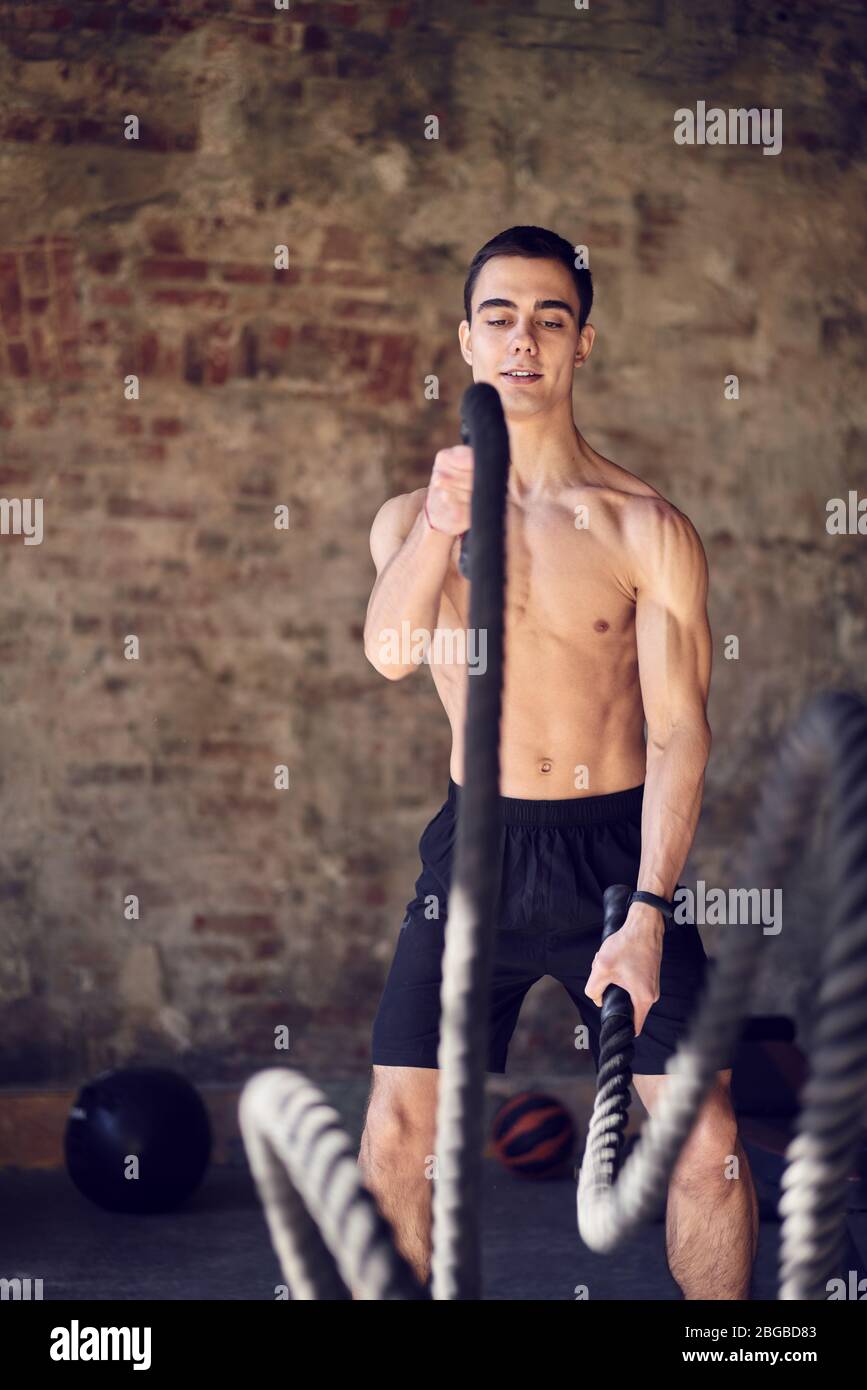 Young man trains battle ropes hi-res stock photography and images - Alamy