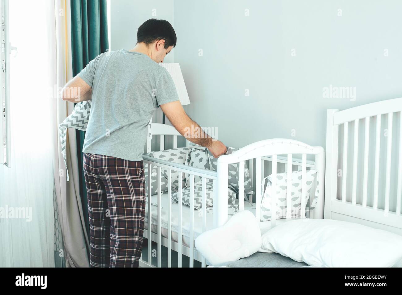 Father helps young mother put on bumpers in the crib. Family lifestyle concept Stock Photo