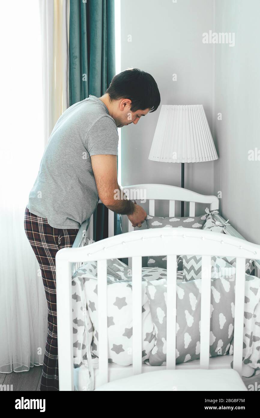 Father helps young mother put on bumpers in the crib. Family lifestyle concept Stock Photo